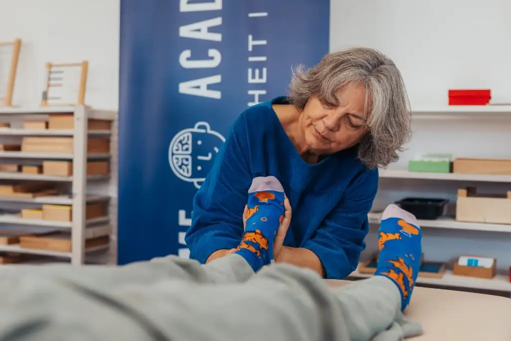 Eine Ergotherapeutin an der Liege bei der Anwendung von Reflexintegrationstechniken. Hier konkret im Rahmen ihrer Ausbildung zur AAIM Reflexintegrationstrainerin.