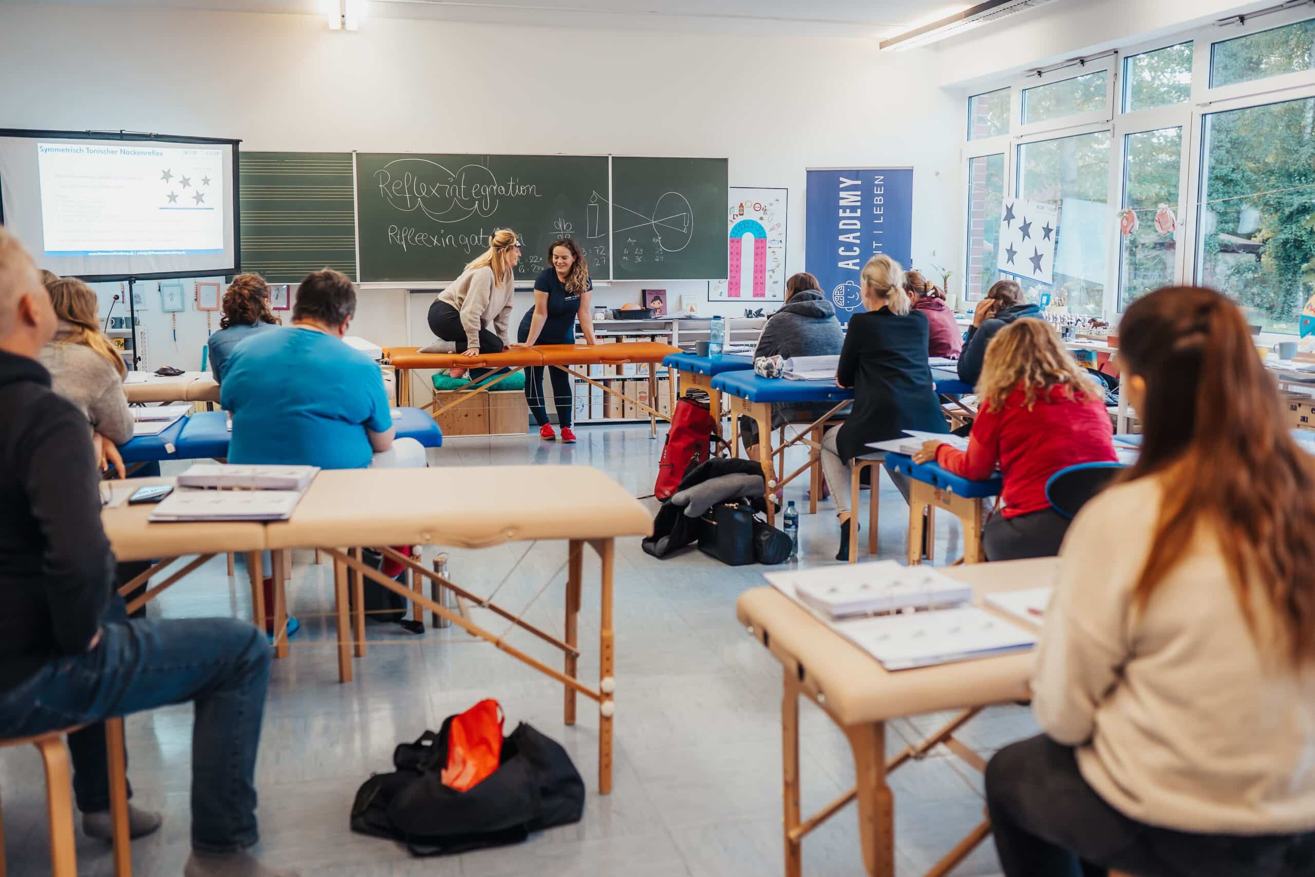 Claudia und Seminarteilnehmerin bei praktischer Übung zur Reflexintegration und Zusehende Teilnehmer