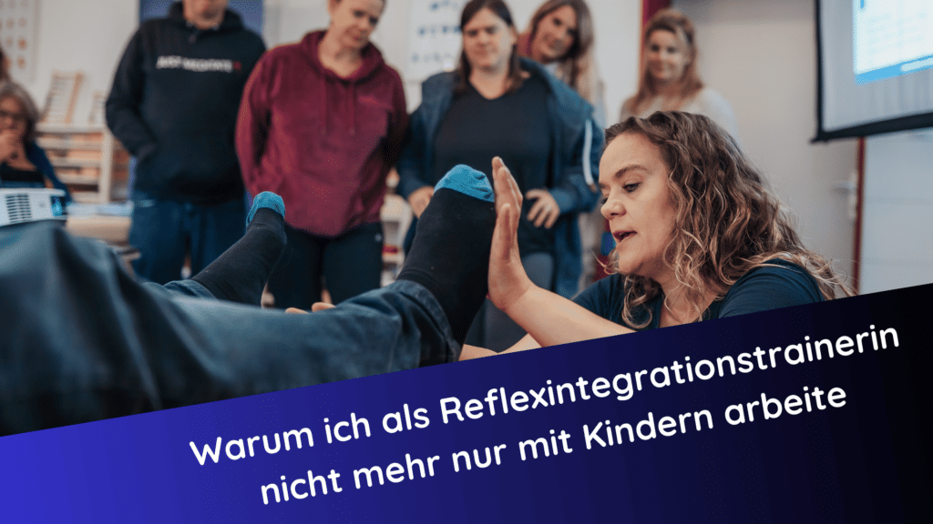 Claudia Hannemann, Reflexintegrationstrainerin demonstriert eine Übung an einer liegenden Person, umgeben von aufmerksamen Teilnehmer:innen in einem Kursraum.