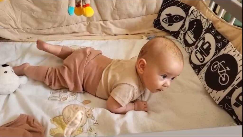 Ein Baby liegt in Bauchlage auf einer weichen Unterlage. Der Kopf ist erhoben, die Arme stützen sich ab – typische Haltung beim Landau-Reflex.