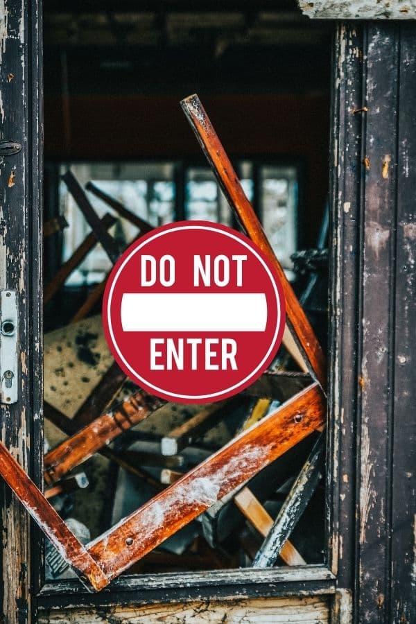Zerstörte Tür mit Holztrümmern, durch die ein ‚Do Not Enter‘-Schild sichtbar ist – Symbolbild für innere Blockaden oder alte Schutzmechanismen.